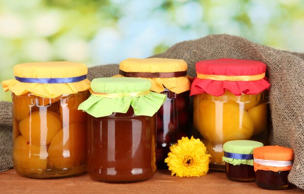 Jars with canned fruit on green background