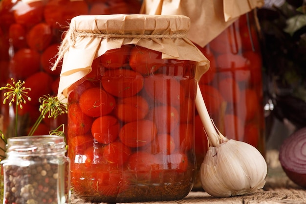 Jars with canned tomatoes on wooden background