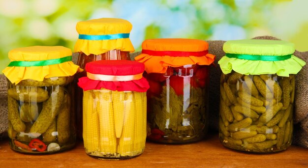 Jars with canned vegetables on green background closeup