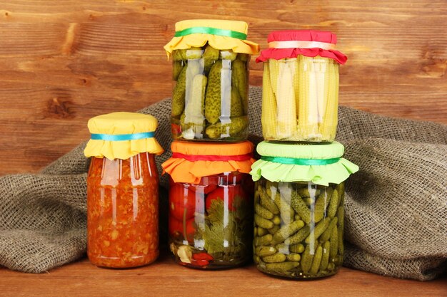 Jars with canned vegetables on wooden background closeup