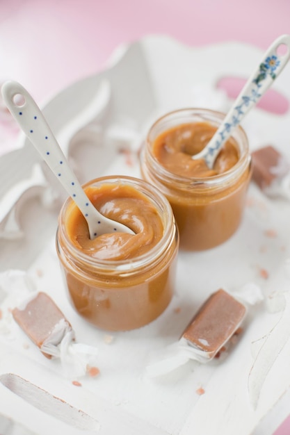 Jars with caramel sauce on tray