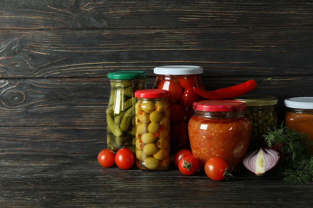 Jars with different canned food on wooden table