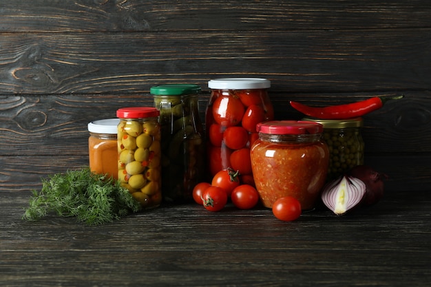 Jars with different canned food on wooden table