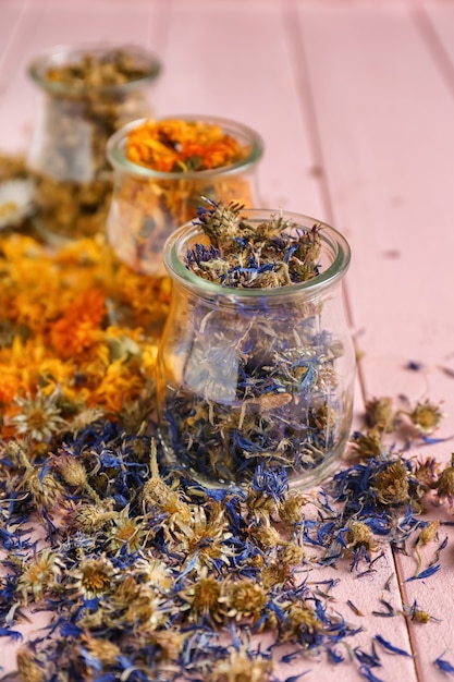 Photo jars with dried flowers on color wooden table