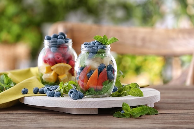 Jars with fruits and berries on wooden board