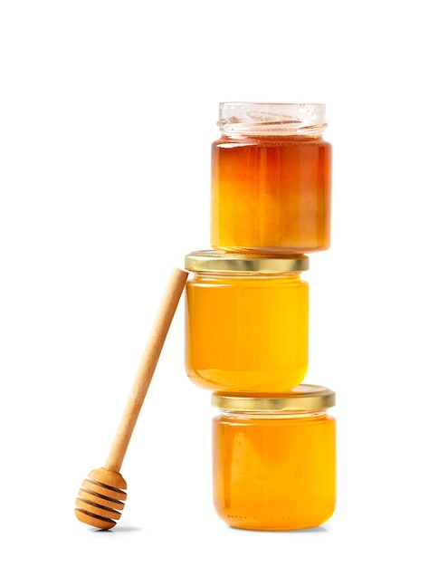 Jars with honey one on top of the other and a stick for honey on a white background