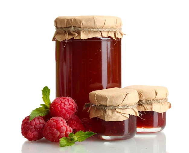 Jars with jam and ripe raspberries with mint isolated on white