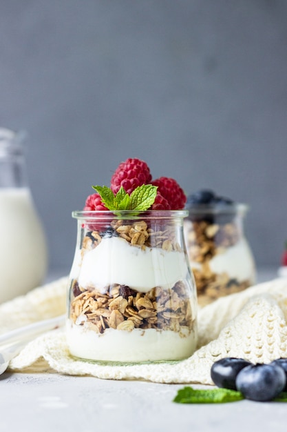 Jars with parfait made of granola, berries and yogurt.