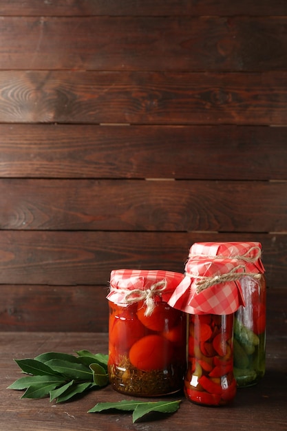 Jars with pickled vegetables on wooden background