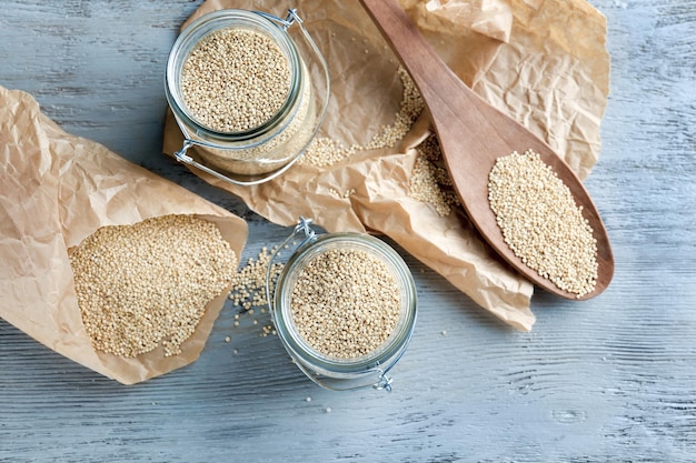 Jars with quinoa seeds on table