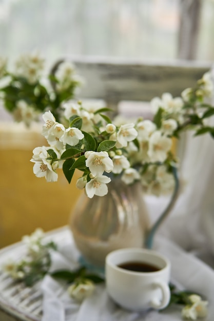 Jasmijn bloemen in een witte vaas. Stilleven met jasmijn en kopje koffie.