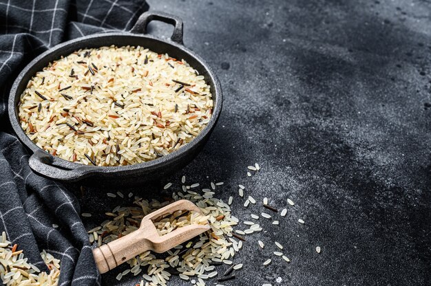 Jasmijn, bruine, rode en zwarte rijst. Gemengde rijst en riceberry. Zwarte achtergrond. Bovenaanzicht. Kopieer ruimte.