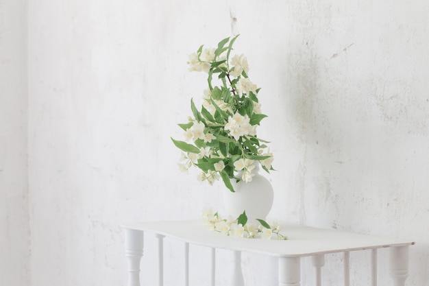 Jasmijnbloemen in vaas op oude muur als achtergrond