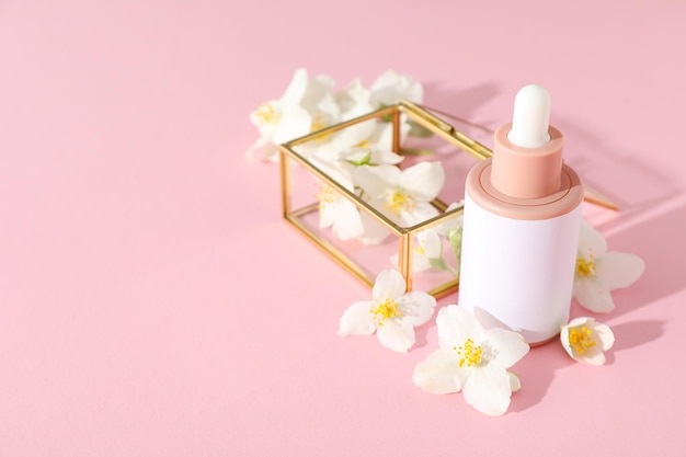 Jasmine bloemen glazen doos en cosmetische fles op roze achtergrondruimte voor tekst