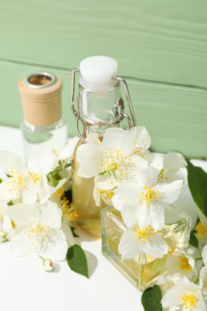 Jasmine flowers and perfume bottles on green wooden background