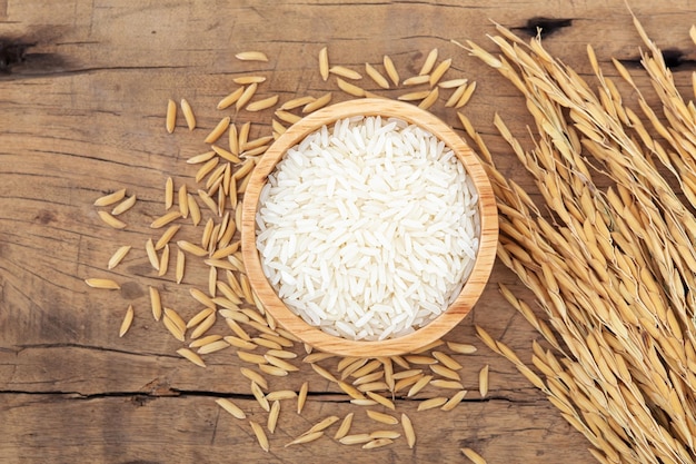 Photo jasmine rice in bowl with paddy on wooden table