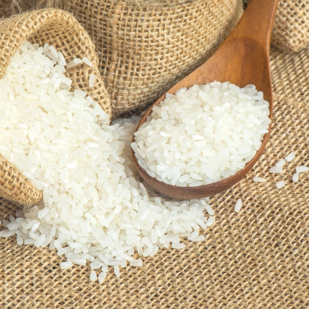 Jasmine rice on wooden scoop with burlap sack