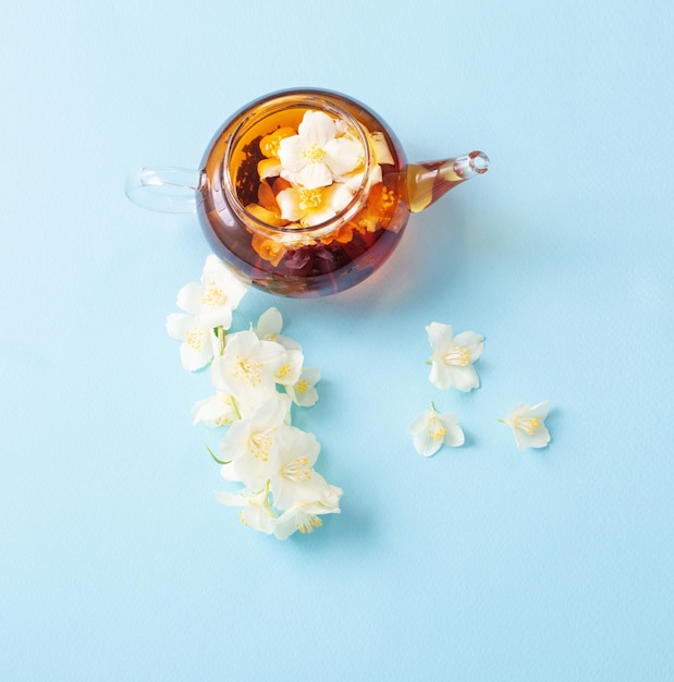 Jasmine tea in glass teapot on blue background