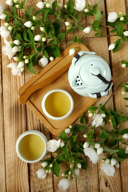 жасминовый чай. Органический цветочный чай. Жасминовый чай в светло-зеленых круглых чашках, чайнике и ветвях жасмина