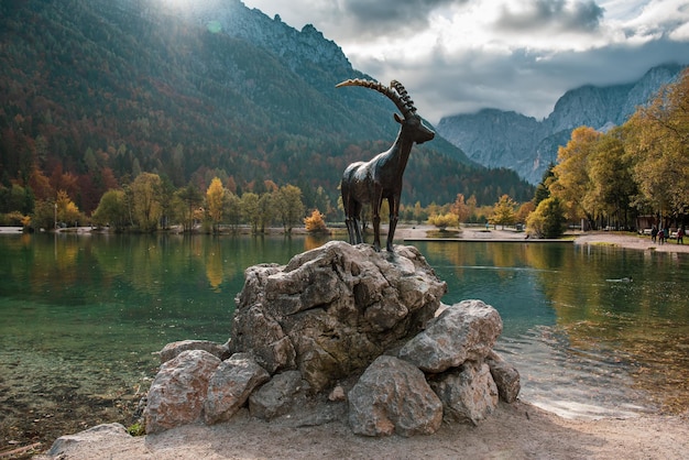 Jasna lake with the monument of the mountain goat chamois at front Triglav National Park Slovenia