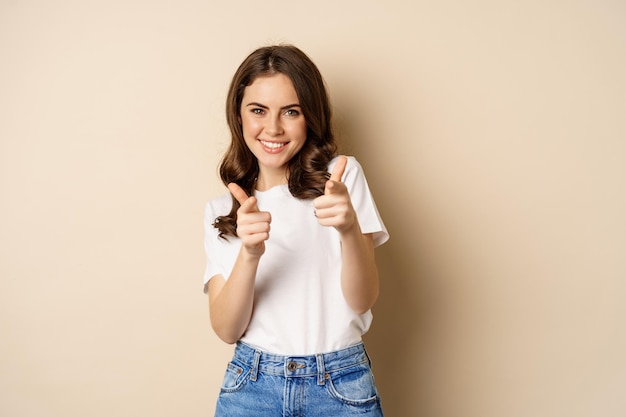 Je hebt deze gefeliciteerd glimlachende jonge vrouw die met de vingers naar de camera wijst, juichend complimenteert met staan...