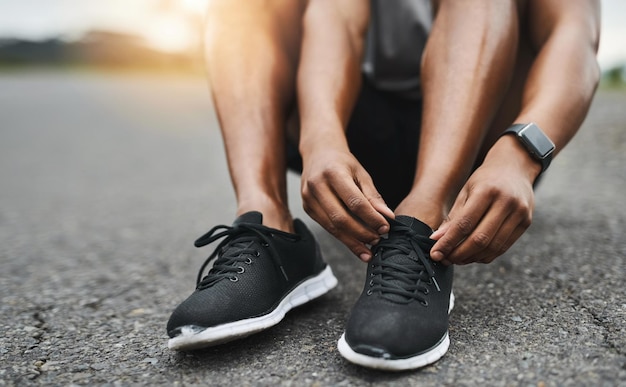 Je kunt het je niet veroorloven om te struikelen Close-up shot van een sportieve man die zijn schoenveters vastmaakt terwijl hij buiten aan het sporten is