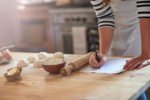 Foto je leert door te doen bijgesneden opname van een vrouw die een recept schrijft voor het deeg dat ze aan het bereiden is