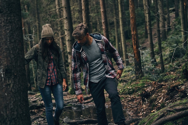 Je moet voorzichtig bewegen. Mooi jong stel samen wandelen in het bos terwijl ze genieten van hun reis