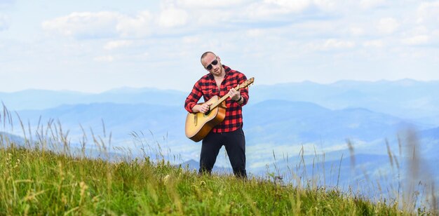 Je muziek vrolijke en vrije cowboy man met akoestische gitaar speler country muziek lied sexy man met gitaar in geruite shirt hipster mode westerse camping en wandelen