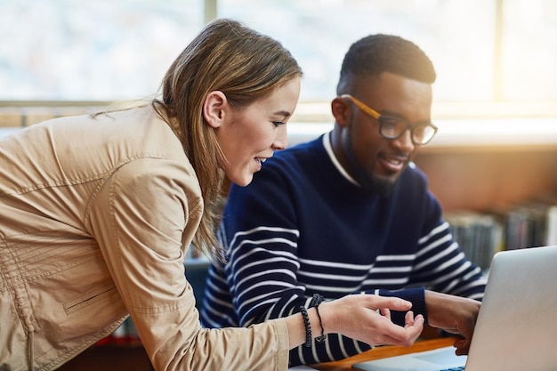Je vindt al je collegenota's nu online Shot van twee universiteitsstudenten die samenwerken op een laptop op de campus