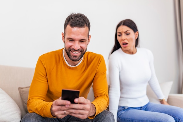 Jealous suspicious mad wife arguing with obsessed husband holding phone texting cheating on cellphone