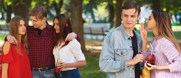 Jealousy and envy in friends relationship. Cheerful young people with detox cocktail having outdoor summer party