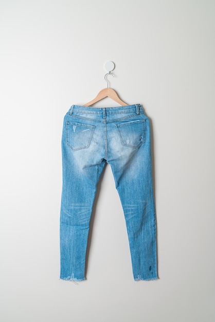 jeans broek hangend met houten hanger aan de muur