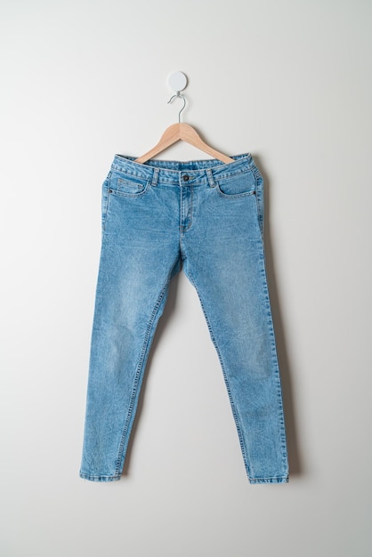 jeans broek hangend met houten hanger aan de muur