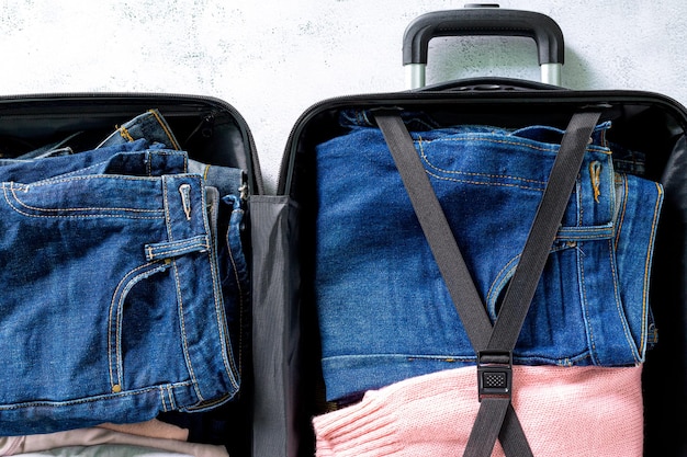 スーツケースの上面図のラゲッジジーンズのジーンズと服スーツケースのパッキング服とジーンズのショット