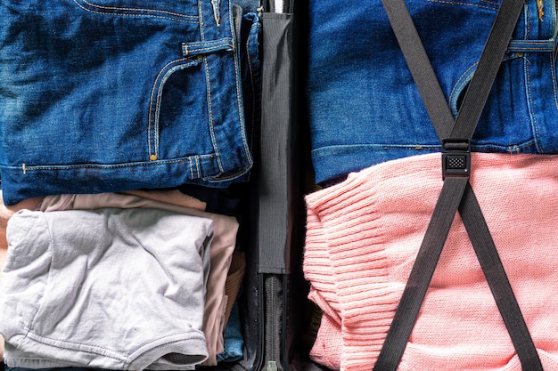 Jeans en kleding in bagage, jeans in koffer bovenaanzicht, koffers inpakken. Shot van kleding en jeans