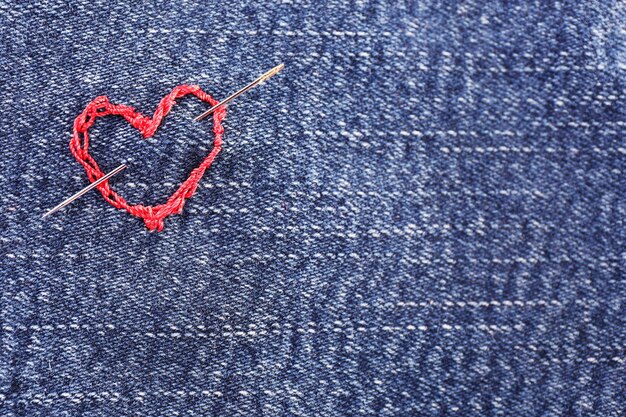 Jeans fabric with red heart embroidered on it, close-up