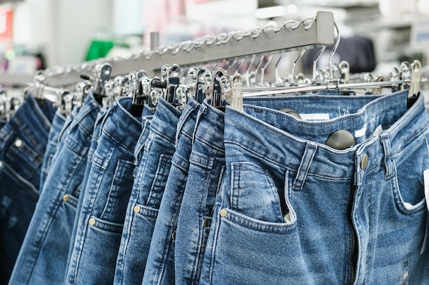 Jeans on hangers on the rack of a retail clothing store