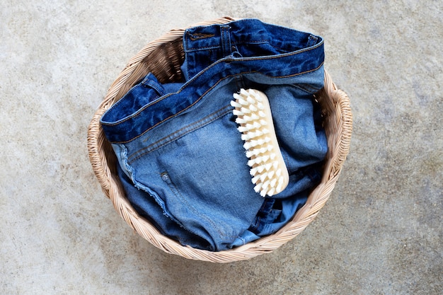 Jeans in wasmand op cementvloer.