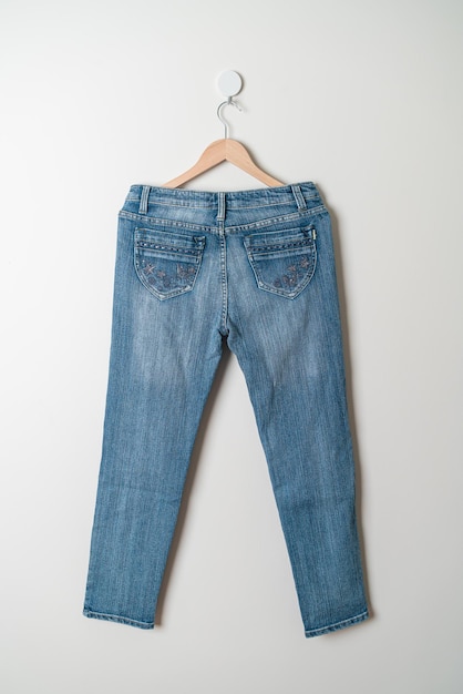 jeans trousers hanging with wood hanger on wall