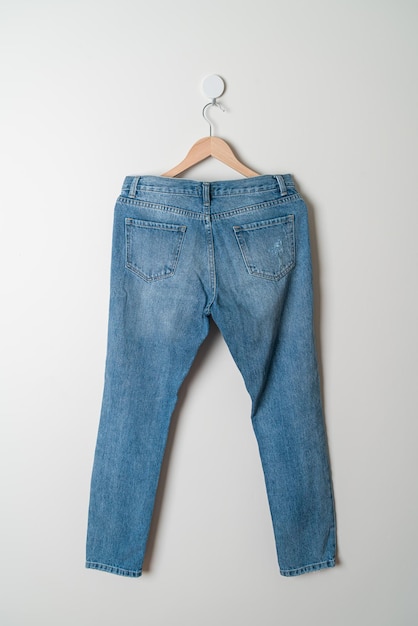 jeans trousers hanging with wood hanger on wall