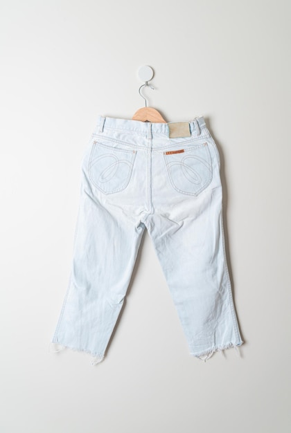 jeans trousers hanging with wood hanger on wall