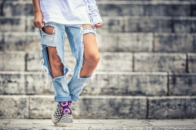 Premium Photo | Jeans with large holes on the legs of a young teenage girl.