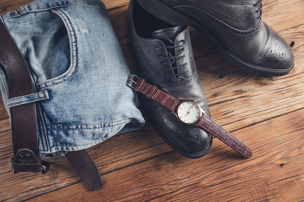 Jeans with shoes and watch and belt on table