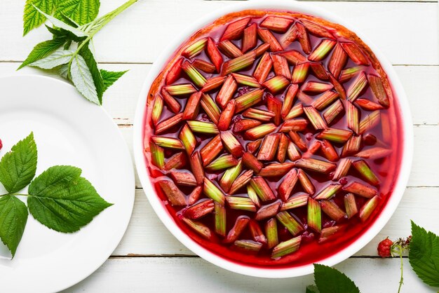 Jellied pie or cake with rhubarb stalks and raspberries. Summer sweet dessert.