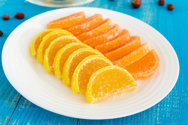 Jelly candies in form citrus slices covered with sugar on a blue background.