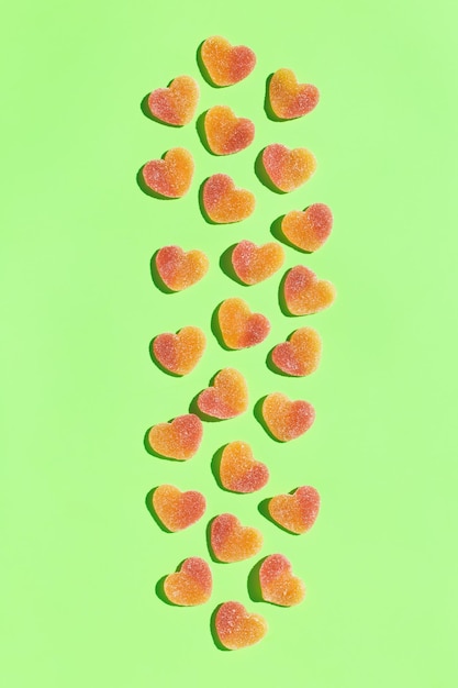 그림자가 있는 민트 녹색 배경에 젤리 하트 모양의 사탕 과자