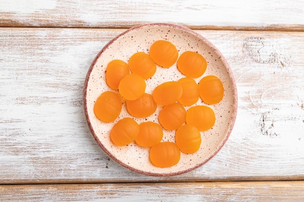 Jelly pumpkin candies on white wooden background top view