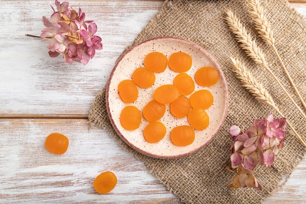 Jelly pumpkin candies on white wooden background