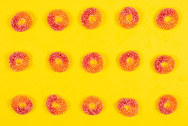 Photo jelly sweets rings on yellow background. pattern.